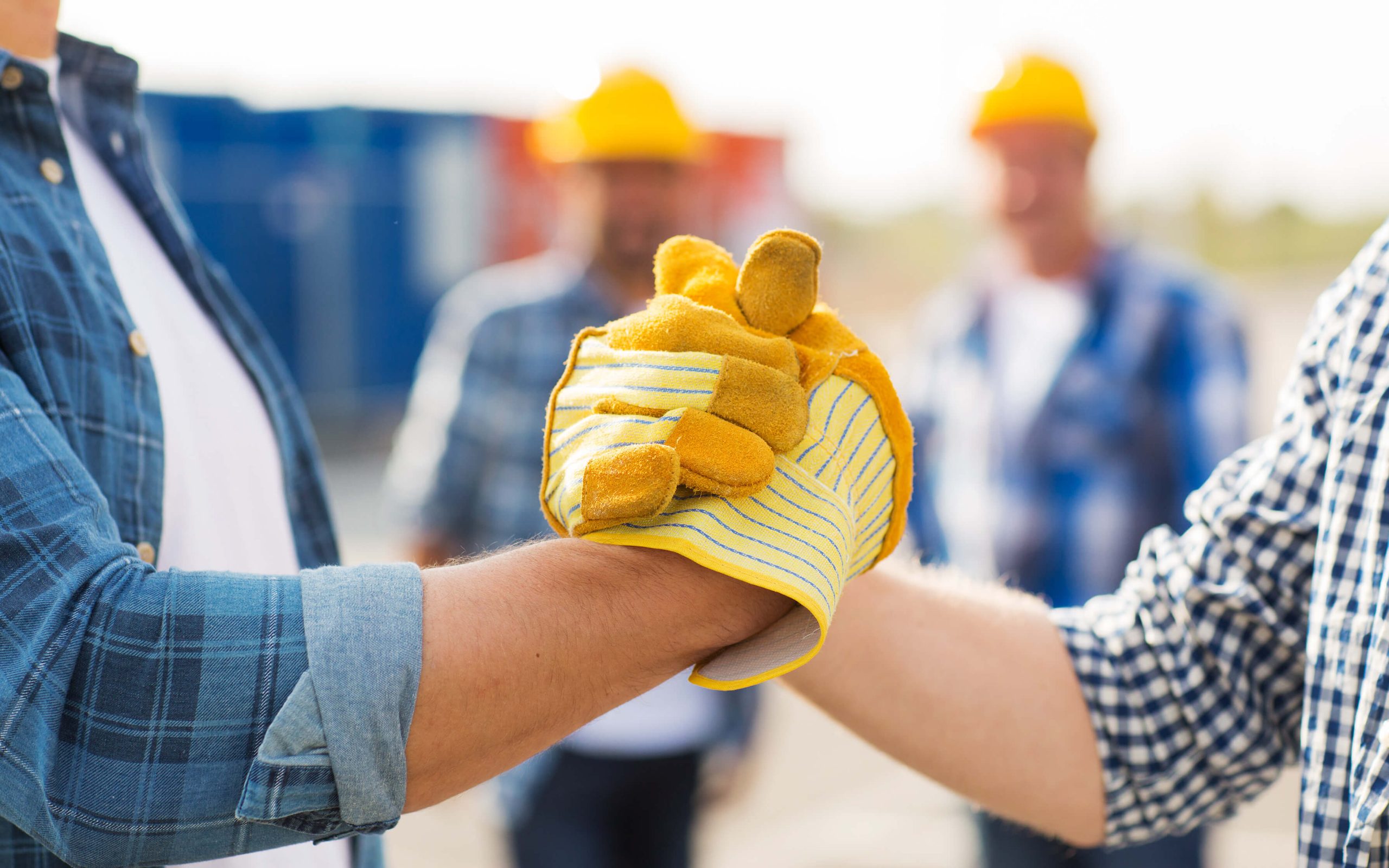 An upclose image of kokua roofing workers shaking hands.